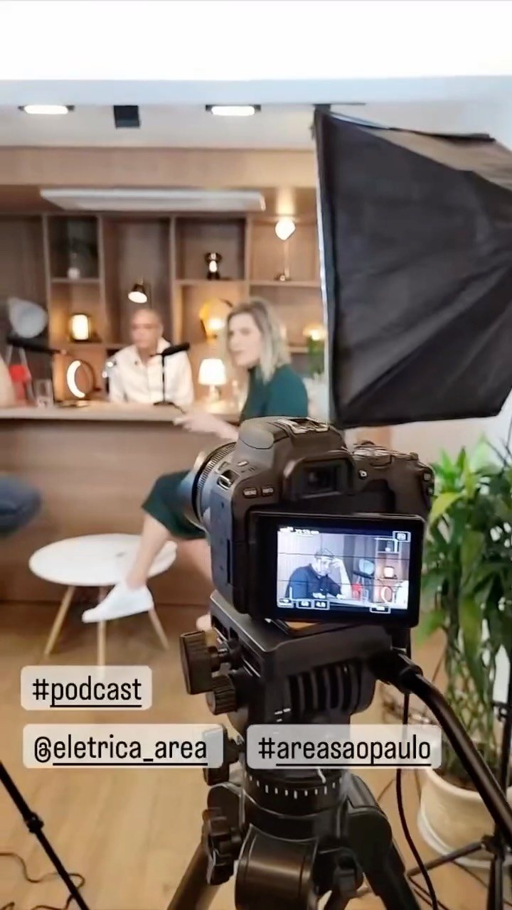 Set de podcast montado com softbox e câmera em tripé, com a cena aparecendo no monitor da câmera