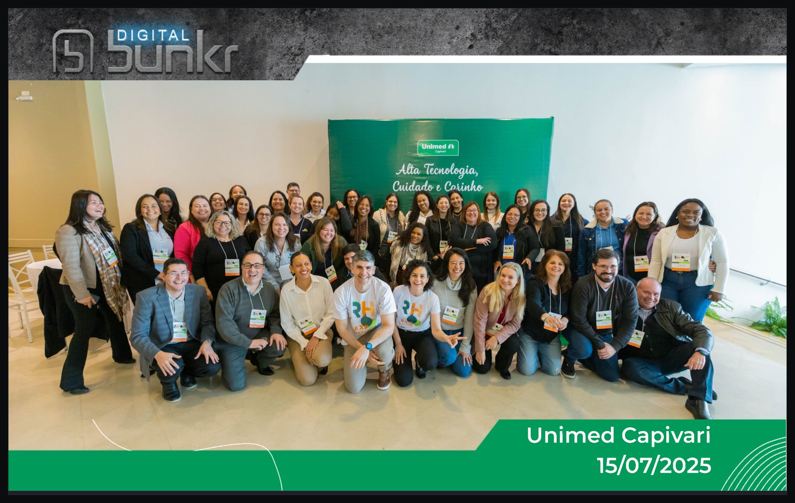 Topo da galeria de um dos eventos: fotografia do grupo de participantes diante do painel, com o nome do evento e a data sobre a imagem